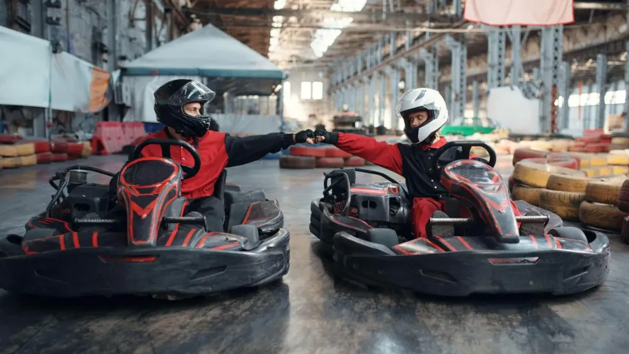 Deux pilotes en karts se donnent un fist bump, prêts pour une course de karting Vaucluse.