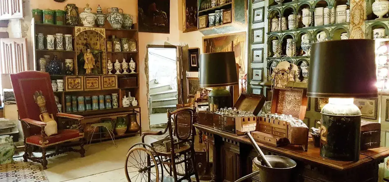 Intérieur d'un **hôtel d'Agar** rempli d'antiquités, de pots en céramique, de meubles anciens et d'une chaise à porteurs.