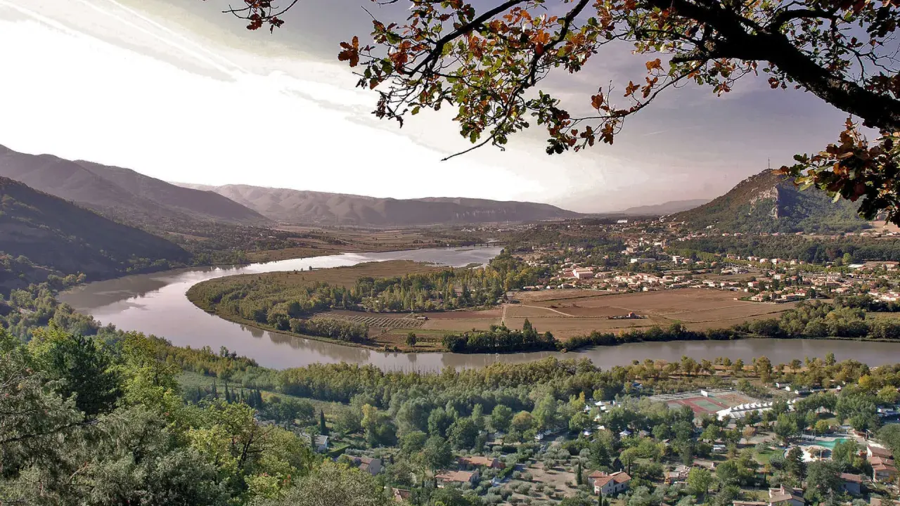 Vue panoramique d'une vallée avec une rivière sinueuse, des vignobles et un village. Idéal pour une randonnée à Pertuis.