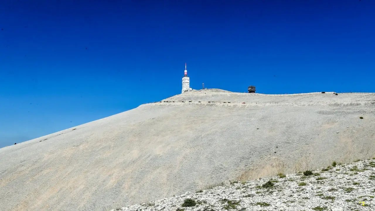 Le Mont Ventoux, sommet aride sous un ciel bleu intense, dominé par une tour de télécommunication.