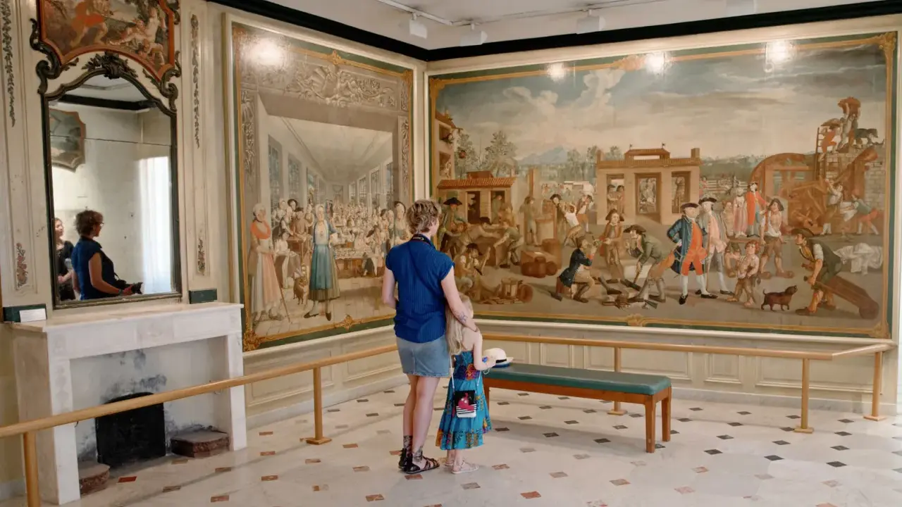 Une mère et sa fille admirent une fresque historique lors d'une exposition dans le Vaucluse.