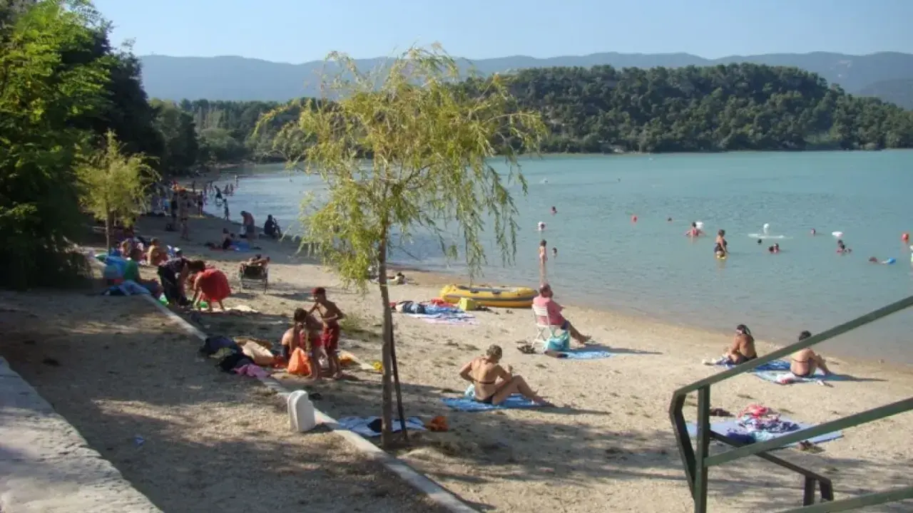 Plage animée à l'étang de la Bonde, baigneurs dans l'eau, familles sur le sable. Avis positif pour ce lieu de détente.