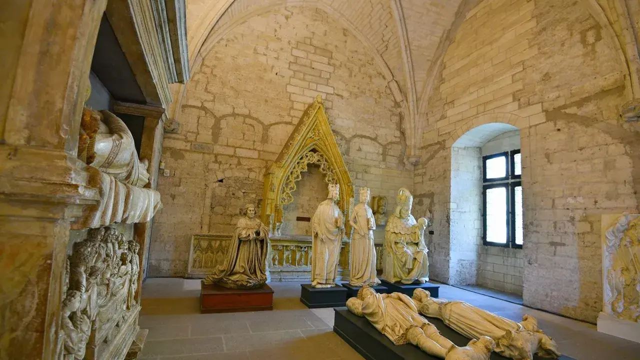 Intérieur du Palais des Papes à Avignon : gisants, statues royales et religieuses sous des voûtes de pierre.