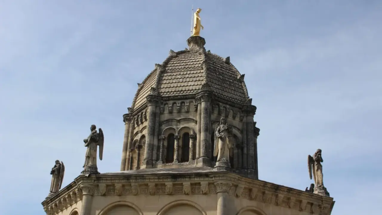 Dôme de Notre Dame de Provence, orné de statues d'anges et surmonté d'une Vierge dorée, sous un ciel bleu.