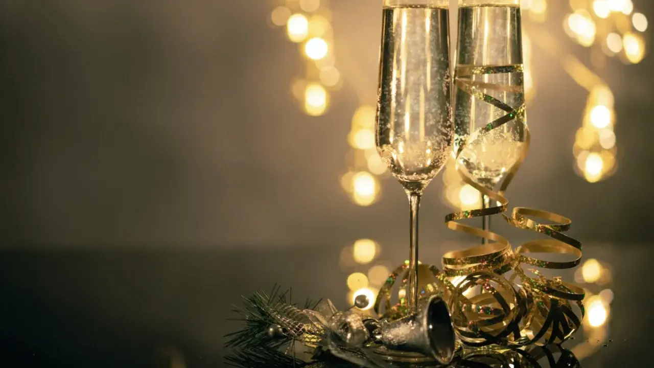 Deux flûtes de champagne pétillant, décorées de rubans dorés, prêtes pour le nouvel an à Avignon. Lumières festives en arrière-plan.