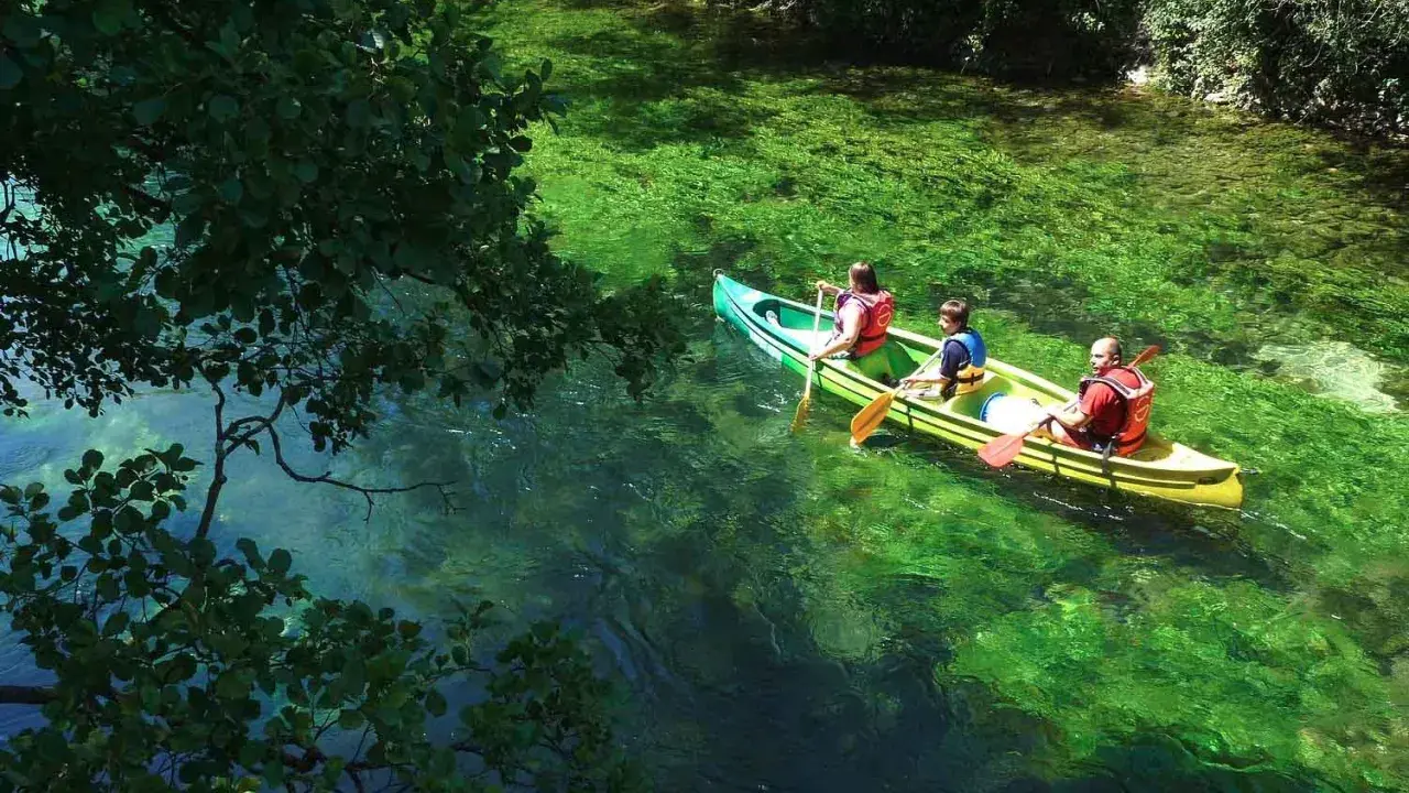 Trois personnes en canoë sur la Durance, profitant d'une baignade rafraîchissante dans des eaux turquoise et verdoyantes.