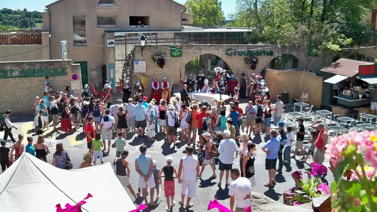 Foule en costume d'époque lors de la fête de la veraison, avec des musiciens et des stands.