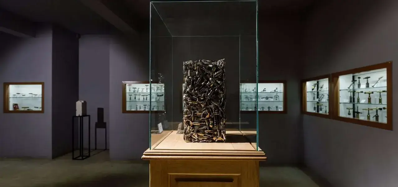Sculpture en tire-bouchons dans une vitrine au musée du tire bouchon. Des vitrines murales exposent d'autres tire-bouchons anciens.