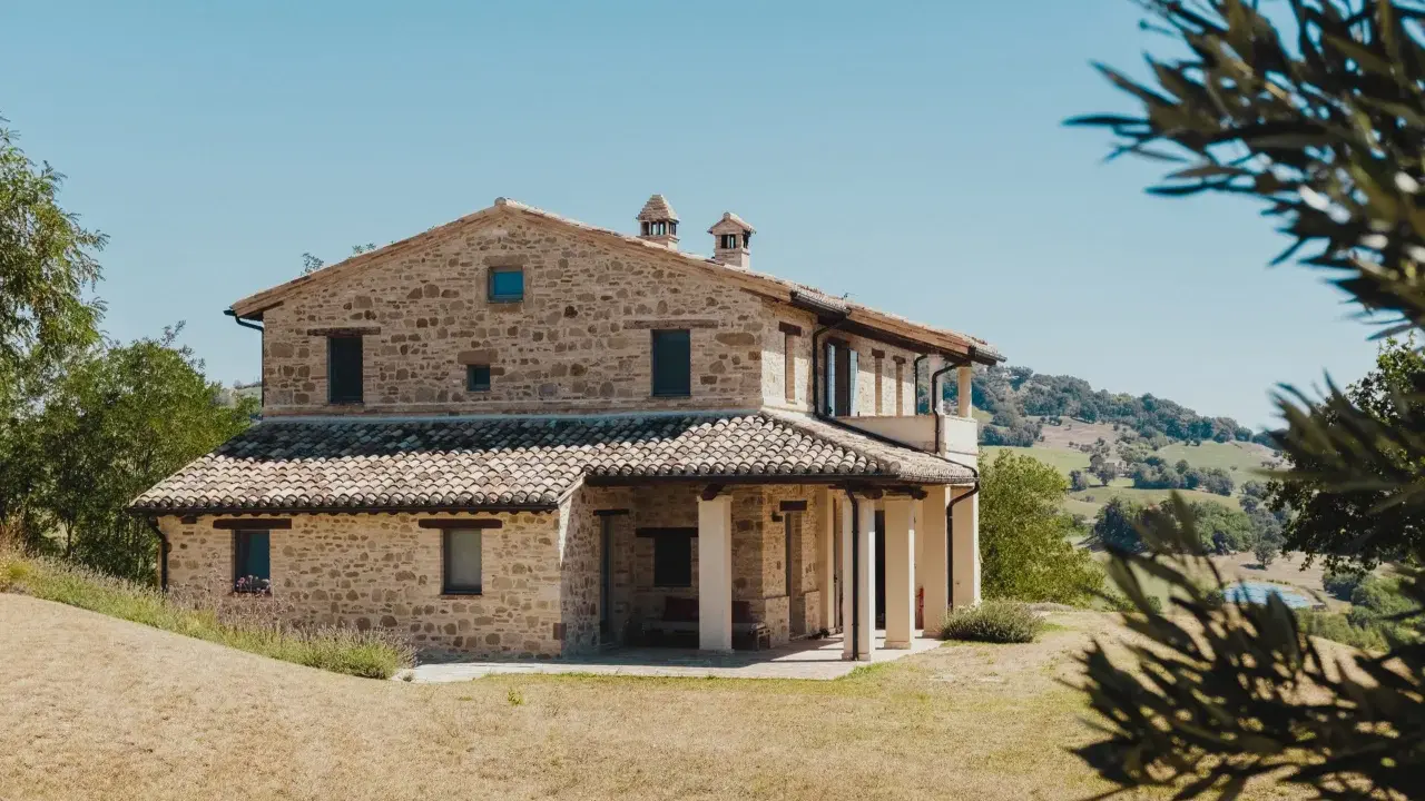 Un mas en pierre typique du sud de la France, niché dans des collines verdoyantes sous un ciel bleu éclatant.
