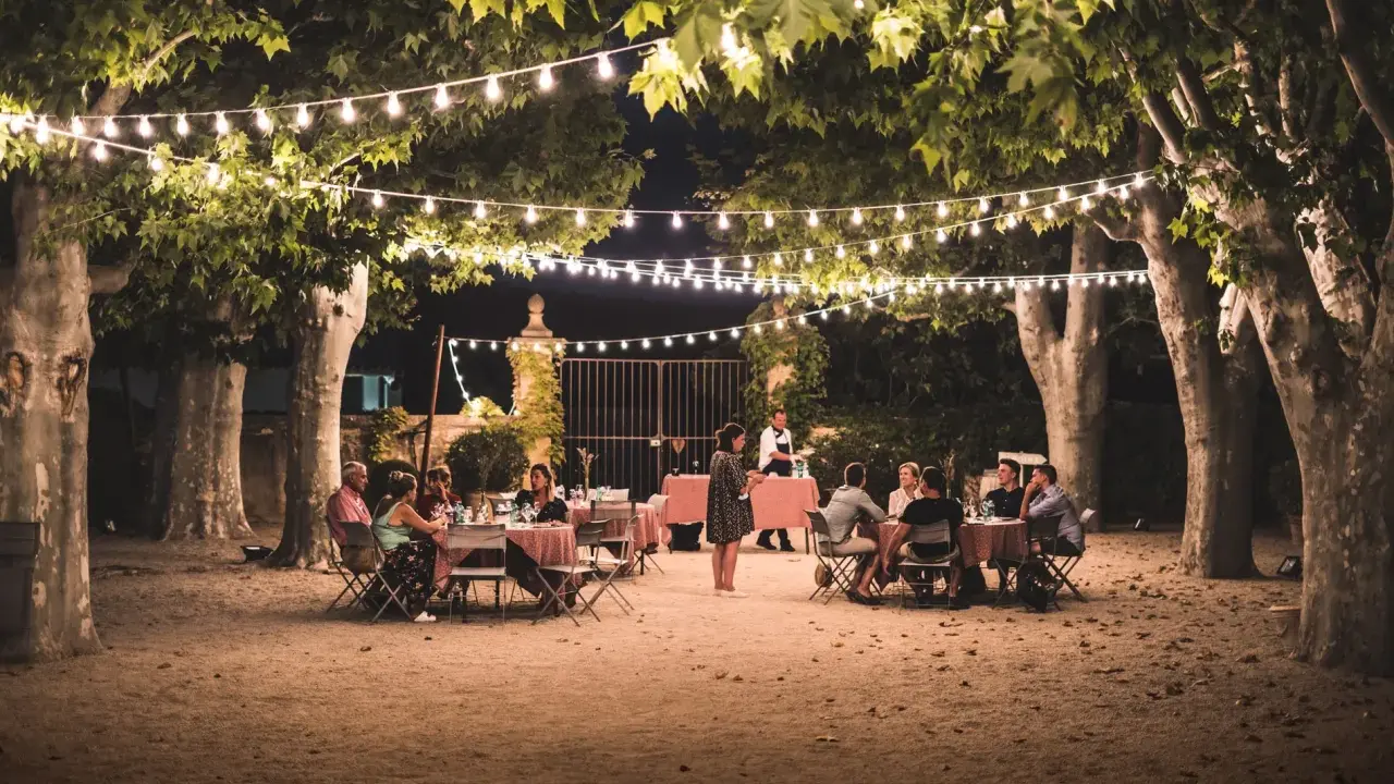 Soirée d'été en Provence sous les guirlandes lumineuses. Un dîner en plein air, parfait pour l'agenda des manifestations en Provence.