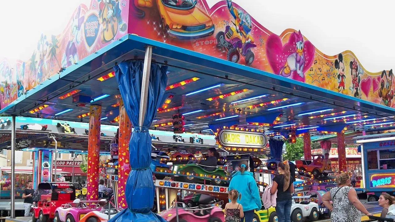 Attraction for children with cars, decorated with Mickey Mouse and friends. A sign says "Paris Dakar".