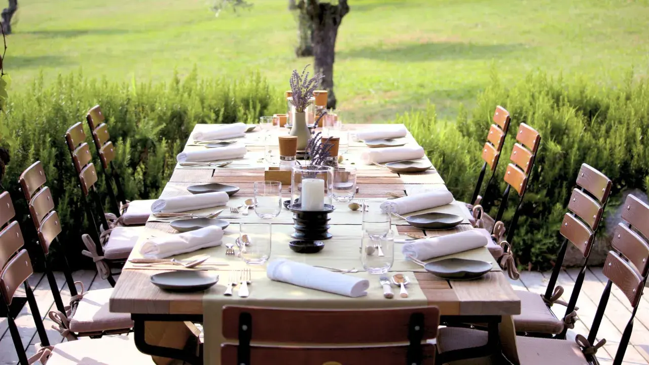 Table dressée pour un repas en plein air, entourée de verdure. Les vignes et son jardin offrent un cadre idyllique pour cette belle table.