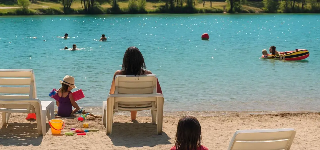 Journée baignade à L'Isle-sur-la-Sorgue. Des enfants jouent dans l'eau turquoise, d'autres sur le sable. Une mère surveille, profitant du soleil.