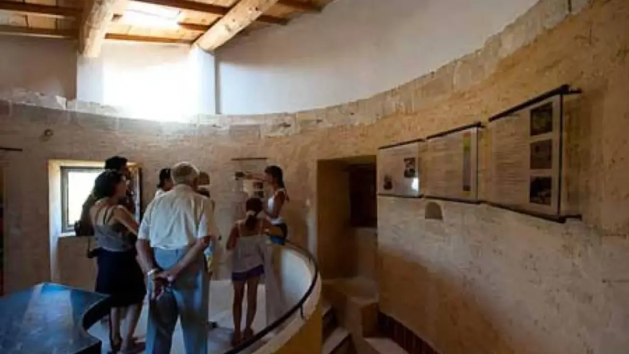 Visite du moulin de Salignan, un groupe découvre les panneaux d'exposition dans l'espace circulaire aux murs de pierre.