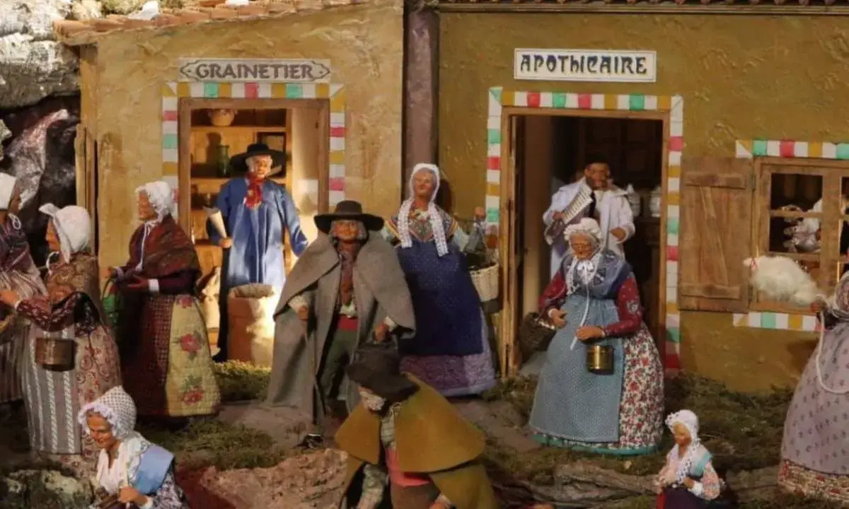 Scène de village provençal avec santons. Découvrez les plus belles crèches de Noël en Provence, avec des personnages costumés devant le grainetier et l'apothicaire.