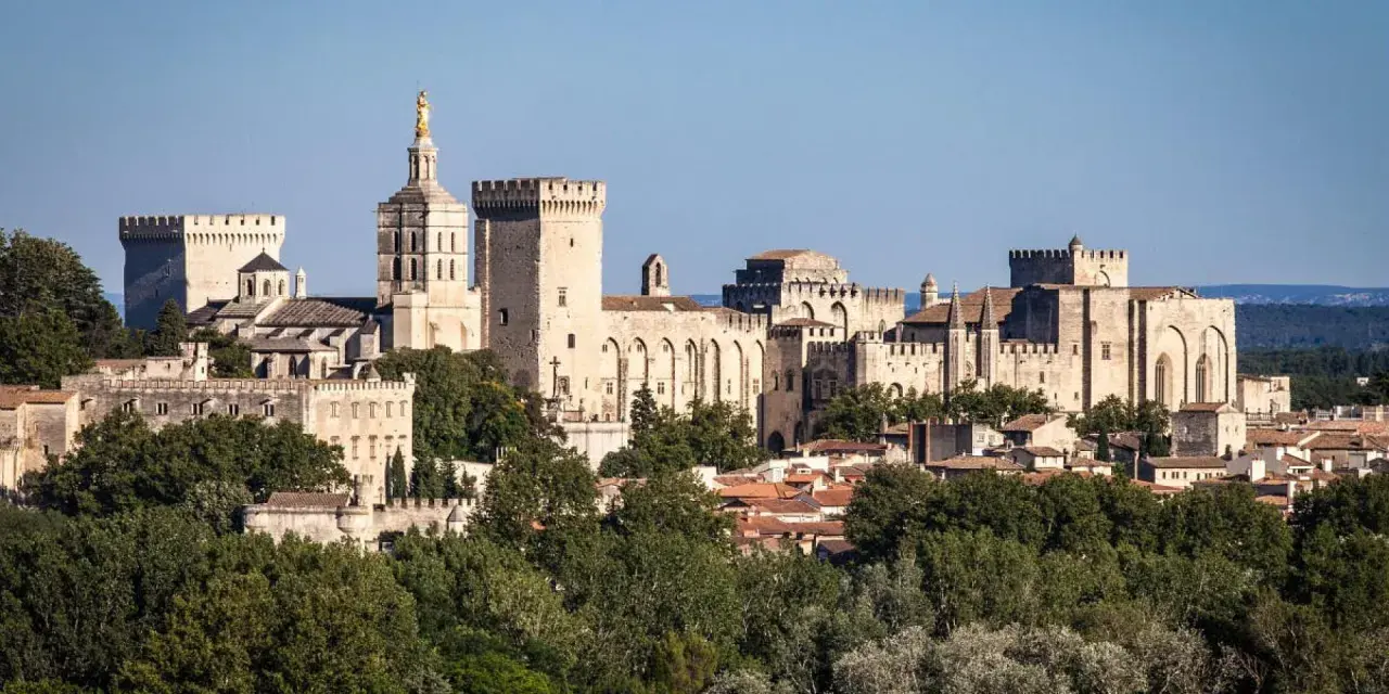 Vue panoramique de la cité des papes, avec le Palais des Papes imposant et ses tours crénelées, baignée de soleil.