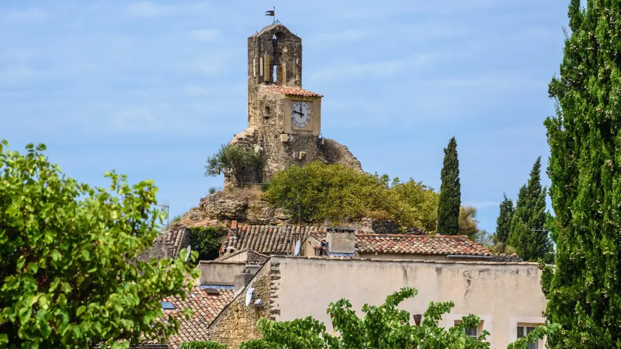 La tour de l'église de Lourmarin, perchée sur une colline rocheuse, domine le village. Un cadran solaire orne son flanc.