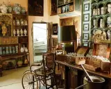Intérieur d'un **hôtel d'Agar** rempli d'antiquités, de pots en céramique, de meubles anciens et d'une chaise à porteurs.