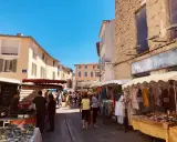 Animation des étals colorés et des passants sous le soleil éclatant du marché de l'Isle-sur-la-Sorgue.