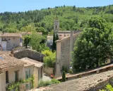 Vue d'un village provençal avec ses toits de tuiles, un clocher et une colline boisée. On imagine le marché de Cereste animé sous le soleil.