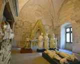 Intérieur du Palais des Papes à Avignon : gisants, statues royales et religieuses sous des voûtes de pierre.