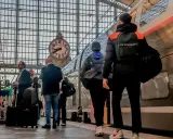 Voyageurs attendant le train pour Apt, sous une grande horloge dans une gare.