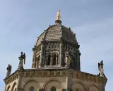 Dôme de Notre Dame de Provence, orné de statues d'anges et surmonté d'une Vierge dorée, sous un ciel bleu.