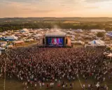 Scène de concert animée lors du festival Monteux, avec une foule immense sous un ciel doré.