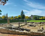 Vestiges romains ensoleillés, parfaits pour visiter Vaison-la-Romaine. Ruines antiques, colonnes et un clocher médiéval en arrière-plan.