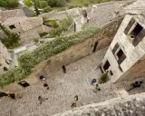 Vue plongeante d'une ruelle pavée bordée de maisons anciennes. Des touristes explorent ce village pittoresque, un peu comme un scad Lacoste, profitant de l'atmosphère paisible.