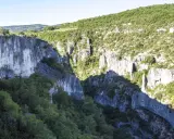 Vue plongeante sur les gorges d'Oppedette, falaises calcaires abruptes couvertes de végétation luxuriante sous un ciel bleu.