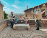 Famille profitant d'une vue panoramique depuis un balcon à Châteauneuf de Gadagne. Le père tient un enfant, tandis que deux autres enfants jouent sur un banc.