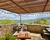 Terrasse d'un restaurant avec vue panoramique sur les collines. Tables dressées sous un auvent de chaume, ambiance estivale. Un jardin sur le toit Saignon promet un repas inoubliable.