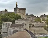 Le Palais des Papes, un incontournable pour tout guide Avignon, se dresse majestueusement. Des touristes explorent ce site historique.
