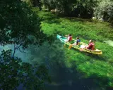 Trois personnes en canoë sur la Durance, profitant d'une baignade rafraîchissante dans des eaux turquoise et verdoyantes.
