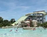 Ambiance estivale dans un parc aquatique Vaucluse. Des familles profitent de la piscine à bouées, sous les imposants toboggans verts et blancs.