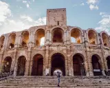 Visiter Arles : une personne tient un bébé sur les marches de l'amphithéâtre romain, sous un ciel bleu et nuageux.