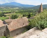 Vue panoramique d'un village provençal avec ses toits de tuiles, sa campagne verdoyante et ses montagnes. Une belle activité gratuite Vaucluse pour s'évader.