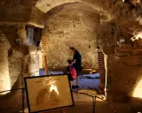 Un homme et un enfant explorent les caves du palais saint-firmin, un lieu historique aux voûtes de pierre.