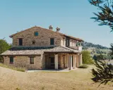 Un mas en pierre typique du sud de la France, niché dans des collines verdoyantes sous un ciel bleu éclatant.