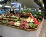 Un étal coloré au marché d'Avignon présente une abondance de fruits et légumes frais : pêches, tomates, haricots verts, radis, aubergines, et plus encore.