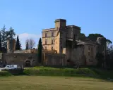 Le majestueux **Château de Lourmarin** se dresse sur une colline, ses pierres ocres baignées de soleil sous un ciel bleu. Des cyprès élancés l'entourent.