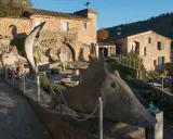 Sculptures étranges devant le musée extraordinaire Ansouis. Un chemin serpente entre des créatures de pierre et des bâtiments en pierre.