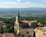 Vue panoramique sur Bonnieux, France, avec son église et ses toits de tuiles, dominant une vallée verdoyante.