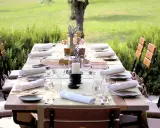 Table dressée pour un repas en plein air, entourée de verdure. Les vignes et son jardin offrent un cadre idyllique pour cette belle table.