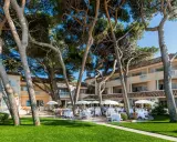 Un magnifique cheval blanc se promène dans un jardin luxuriant en Provence, près d'un hôtel de luxe avec terrasse.