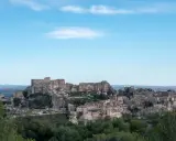 Vue panoramique du village perché des Baux-de-Provence, avec son château médiéval en ruines dominant les maisons de pierre et la végétation verdoyante.