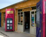 L'entrée colorée du musée des ocres, avec un panneau "Ouvert" et des affiches "Bienvenue".