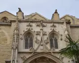 Détail architectural d'une cathédrale, un joyau du tourisme à Carpentras. Gargouilles et fenêtres gothiques sous un ciel couvert.