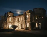 Un château illuminé sous un ciel étoilé et une lune croissante. Les fenêtres brillent, invitant à découvrir les mystères des nuits du château.
